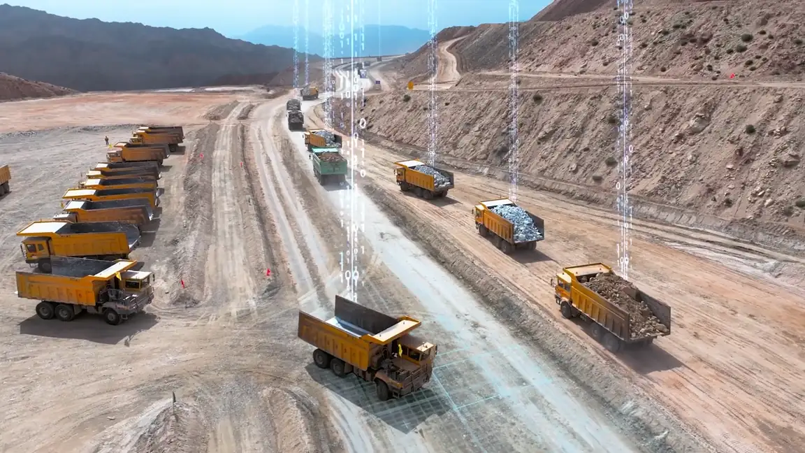 Flota de camiones de acarreo circulando por la vía de un tajo abierto, vista desde el aire.